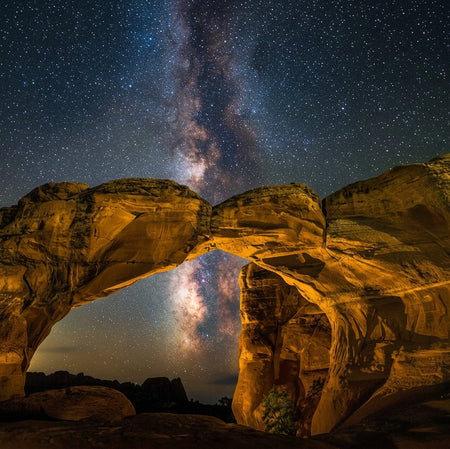 Rocks arching over a starry night sky with the Milky Way visible