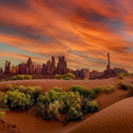 Desert landscape with rock formations and a vibrant sunset sky.